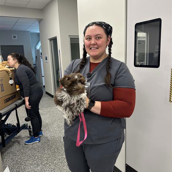 smiling female veterinary technician holding small fluffy dog